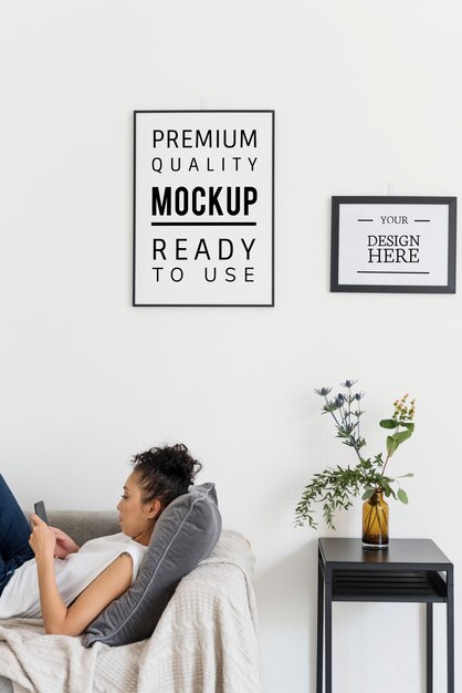 PSD woman relaxing with mockup frames hanging on the wall