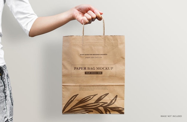 Woman's hand holding an empty brown paper bag mockup Packaging template