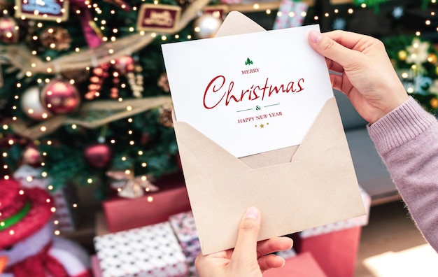 Woman's hand holding merry christmas greeting card mockup Merry christmas and happy new year concept