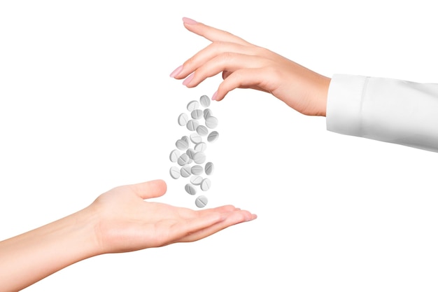 A woman's hand in a white medical coat pours white pills on isolated transparent background