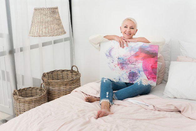 PSD woman sitting in bed and holding a mock-up banner