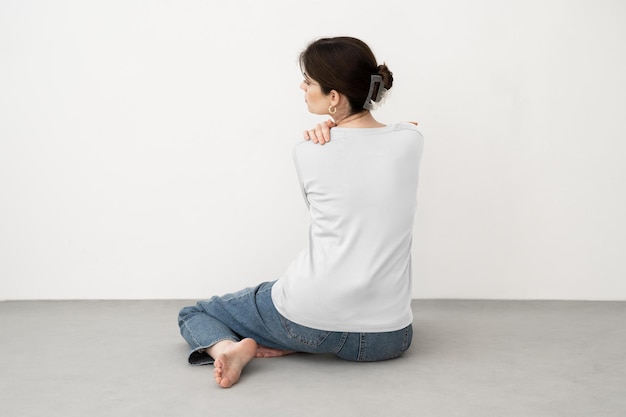 Woman Sitting on the Floor in a Grey Shirt and Blue Jeans