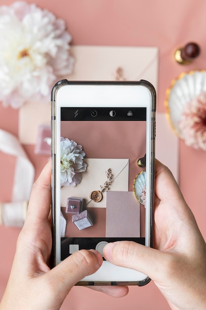 Woman taking a photo of a wedding ring and an invitation