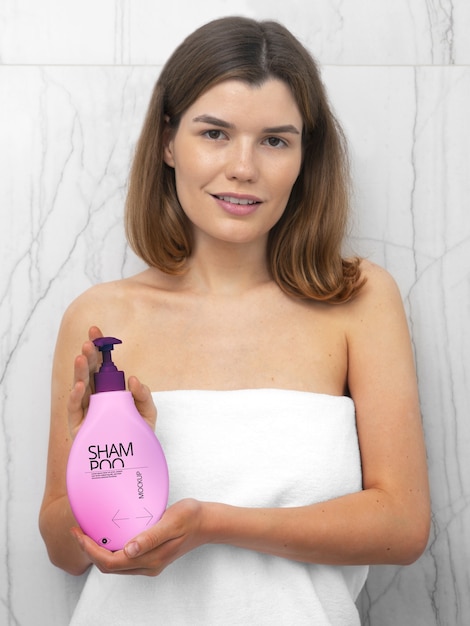 PSD woman in towel holding mock-up bottle of shampoo