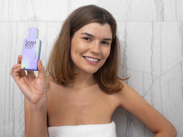 PSD woman in towel holding mock-up bottle of shampoo