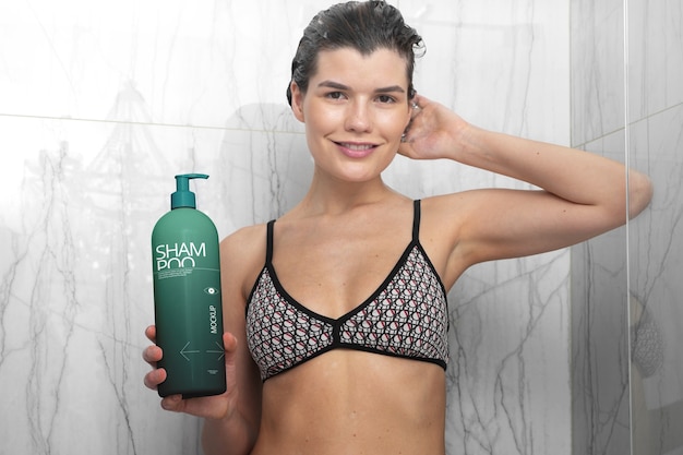 Donna che utilizza una bottiglia di shampoo modello sotto la doccia