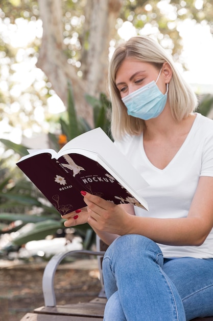 woman wearing mask on street reading book