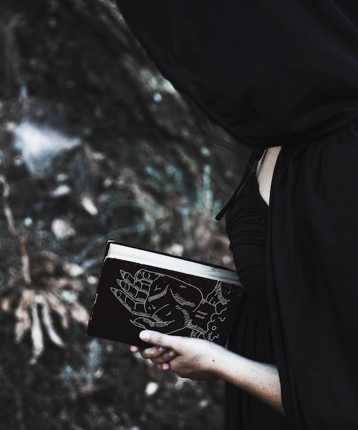 Woman with black hood reading from a spell book