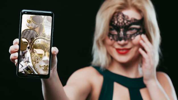 woman with carnival mask showing smartphone mockup