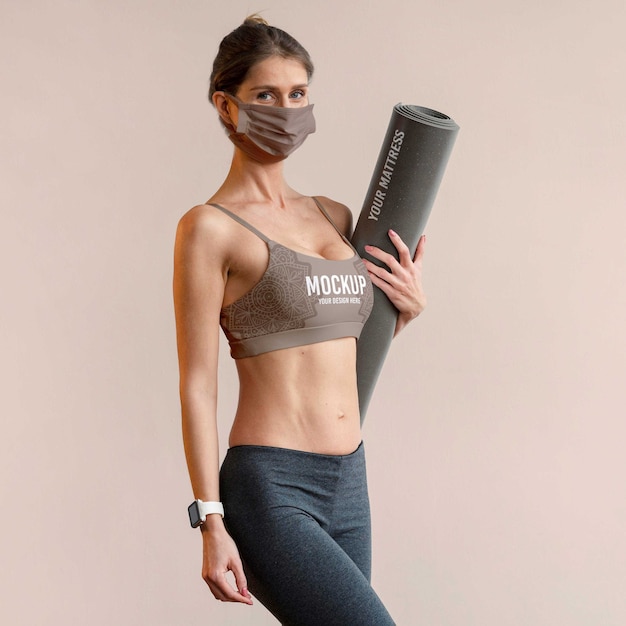 Woman with face mask holding yoga mat