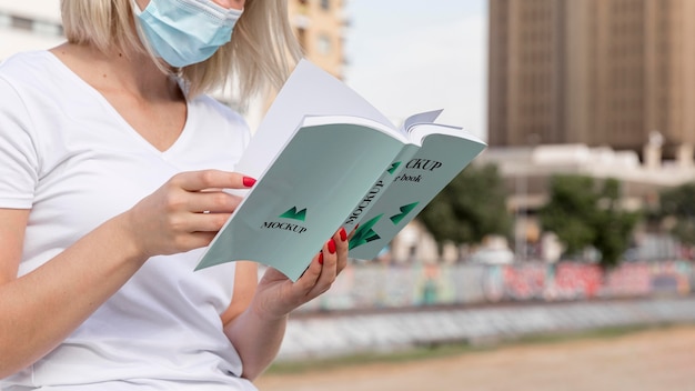 PSD woman with mask reading book on street