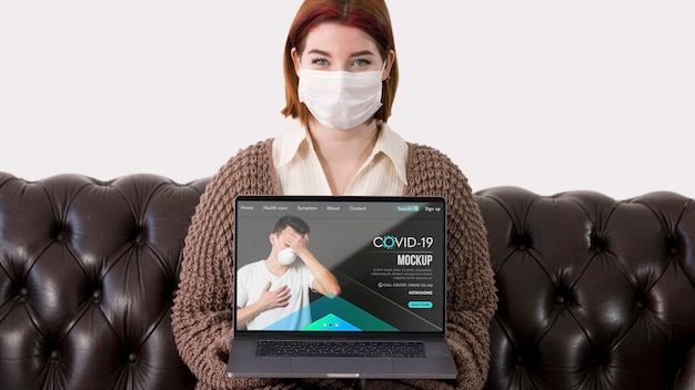 PSD woman with masks holding laptop while sitting on the couch