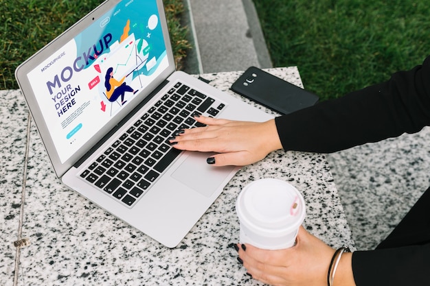 Woman working on laptop outdoors mock-up