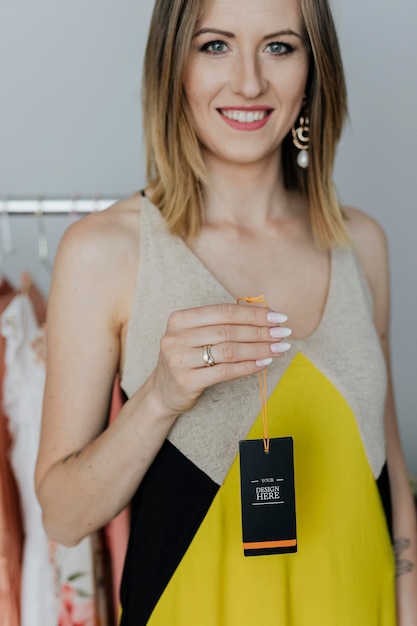 woman in a yellow dress holding a black tag mockup