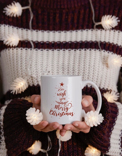 Women hand holding white ceramic coffee cup with light decoratio