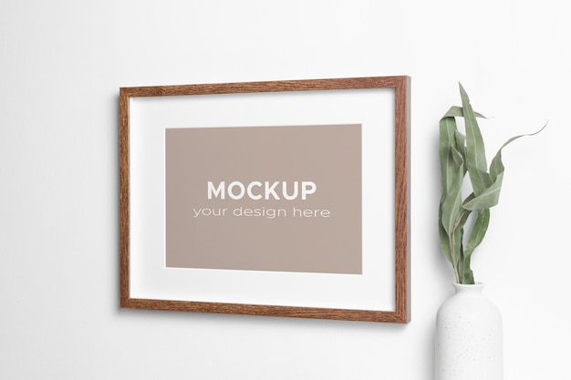 PSD wooden frame mockup on white wall with dry eucalyptus