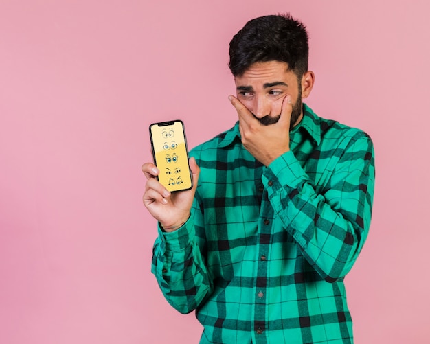 Взволнованный молодой человек держит макет сотового телефона