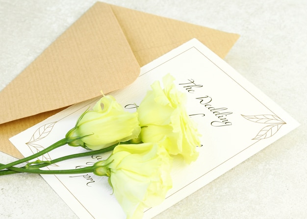 회색 배경에 노란 장미, 봉투 및 초대 카드