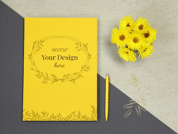 Mockup di carta gialla estiva con fiori, penna e clip d'oro