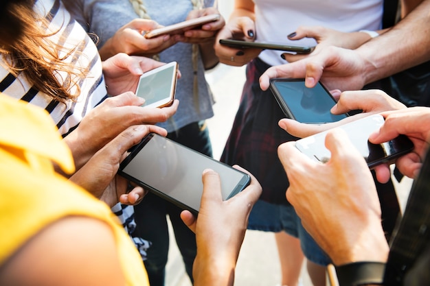 Young adult friends using smartphones together outdoors youth culture concept