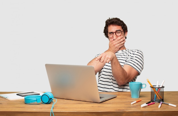 young bearded graphic designer with a laptop laughing hard at something hilarious