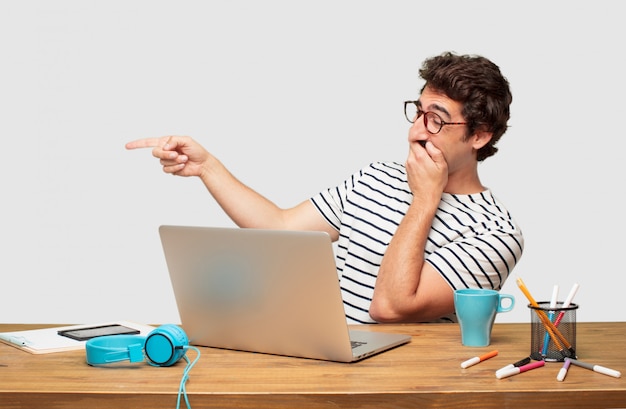 Young bearded graphic designer with a laptop laughing hard at something hilarious