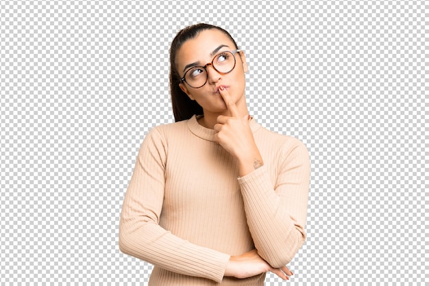 孤立したクロマキー背景の若い美しい女性は見上げながら疑いを持っています