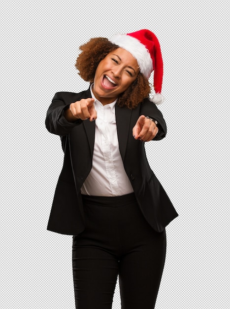 Giovane donna di affari nera che porta un cappello della santa di natale allegro e sorridente