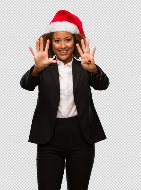 Young black businesswoman wearing a christmas santa hat showing number nine