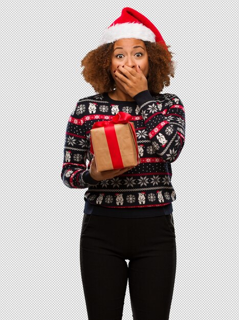 크리스마스에 선물을 들고 젊은 흑인 여성이 매우 무서워하고 두려워 숨겨진