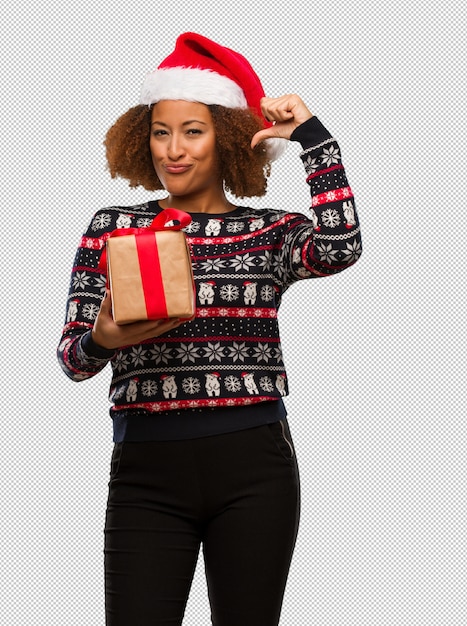 Young black woman holding a gift in christmas day pointing fingers, example to follow
