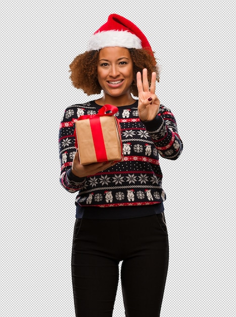 PSD young black woman holding a gift in christmas day showing number three