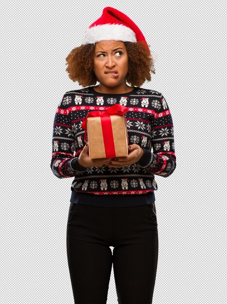 PSD young black woman holding a gift in christmas day thinking about an idea