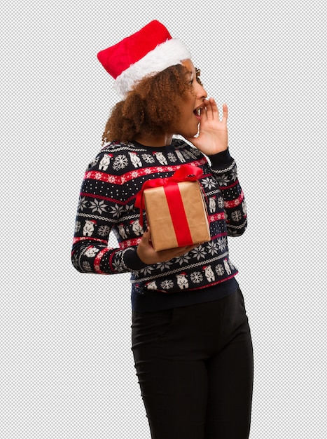 PSD young black woman holding a gift in christmas day whispering gossip undertone