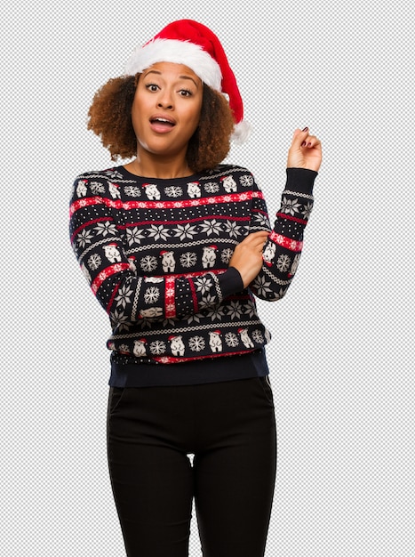 トレンディなクリスマスセーターの若い黒人の女性が指で指を指しているプリント