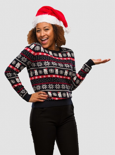 Молодая чернокожая женщина в модный рождественский свитер с принтом, холдинг что-то с рукой