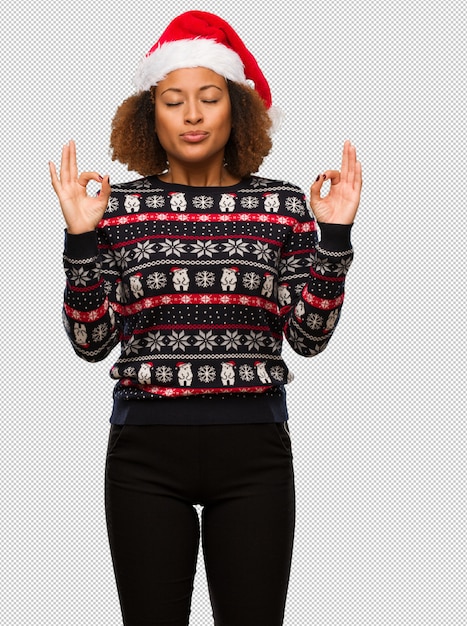 Young black woman in a trendy christmas sweater with print performing yoga