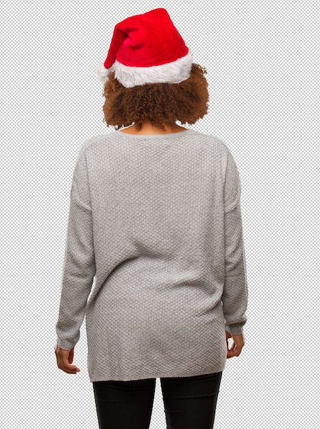 Young black woman wearing a santa hat from behind, looking back