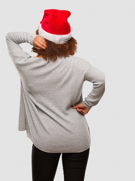 Young black woman wearing a santa hat from behind thinking about something