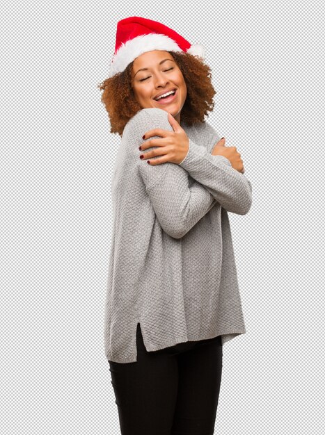 Young black woman wearing a santa hat giving a hug