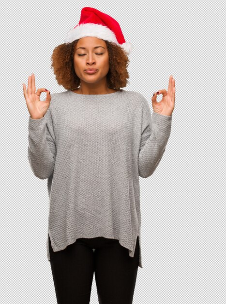 Young black woman wearing a santa hat performing yoga