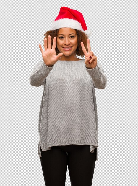 Young black woman wearing a santa hat showing number seven