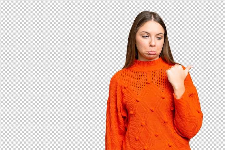 PSD young blonde woman over isolated chroma key background unhappy and pointing to the side