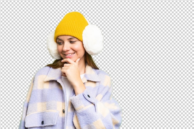 Young blonde woman wearing winter muffs over isolated chroma key background looking to the side