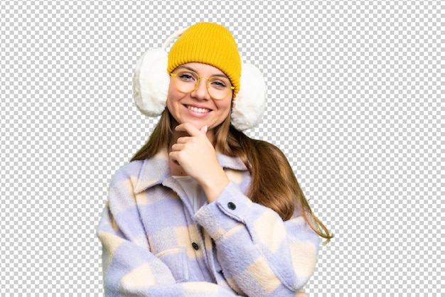 Young blonde woman wearing winter muffs over isolated chroma key background with glasses and smiling
