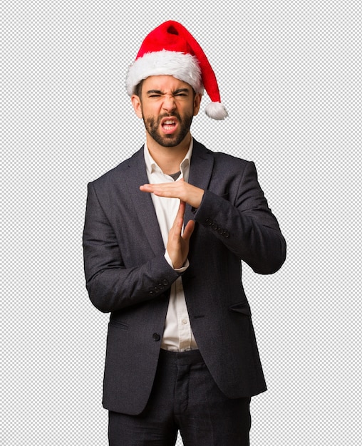 Young business man wearing santa hat doing a timeout gesture