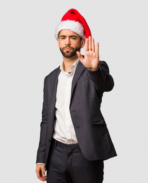 Молодой бизнесмен носить шляпу Санта положить руку в передней