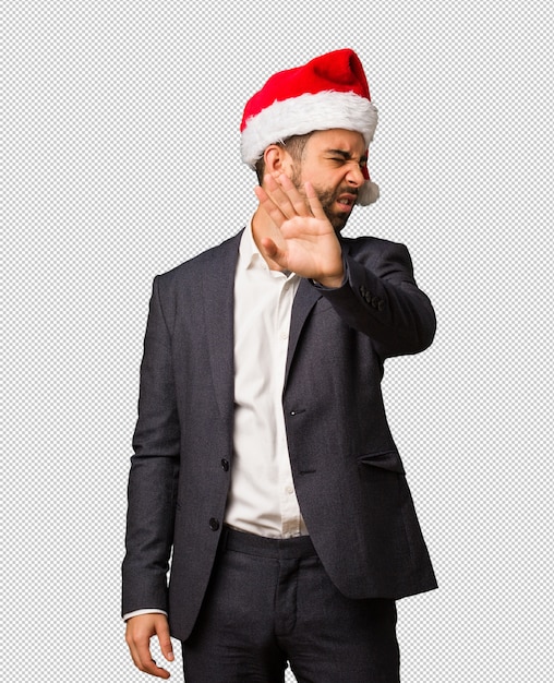 Young business man wearing santa hat putting hand in front