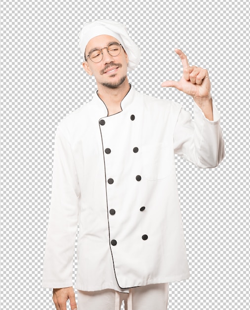 Young chef doing a gesture of small size with his hand