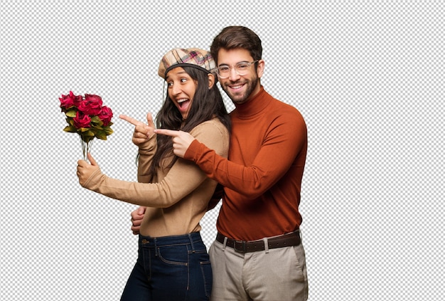 Young couple in valentines day pointing to the side with finger
